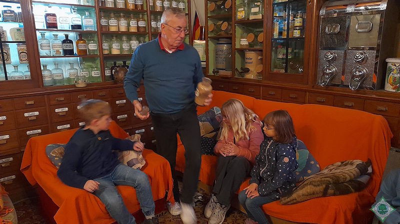Heinz Töns (Mitte) erläutert den Kindern die Arzneimittel im Drogeriemuseum Töns. Foto: Silvia Lütkehellweg