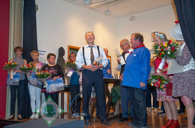 Blumen, den neuen Naturkalender des Heimatvereins und ein flüssiges Dankeschön überreichte Vereinsvorsitzender Franz-Josef Naber (in Kiepenkerl-Tracht) den Beteiligten bei der Abschlussvorstellung. Foto: Holger Martsch img1
